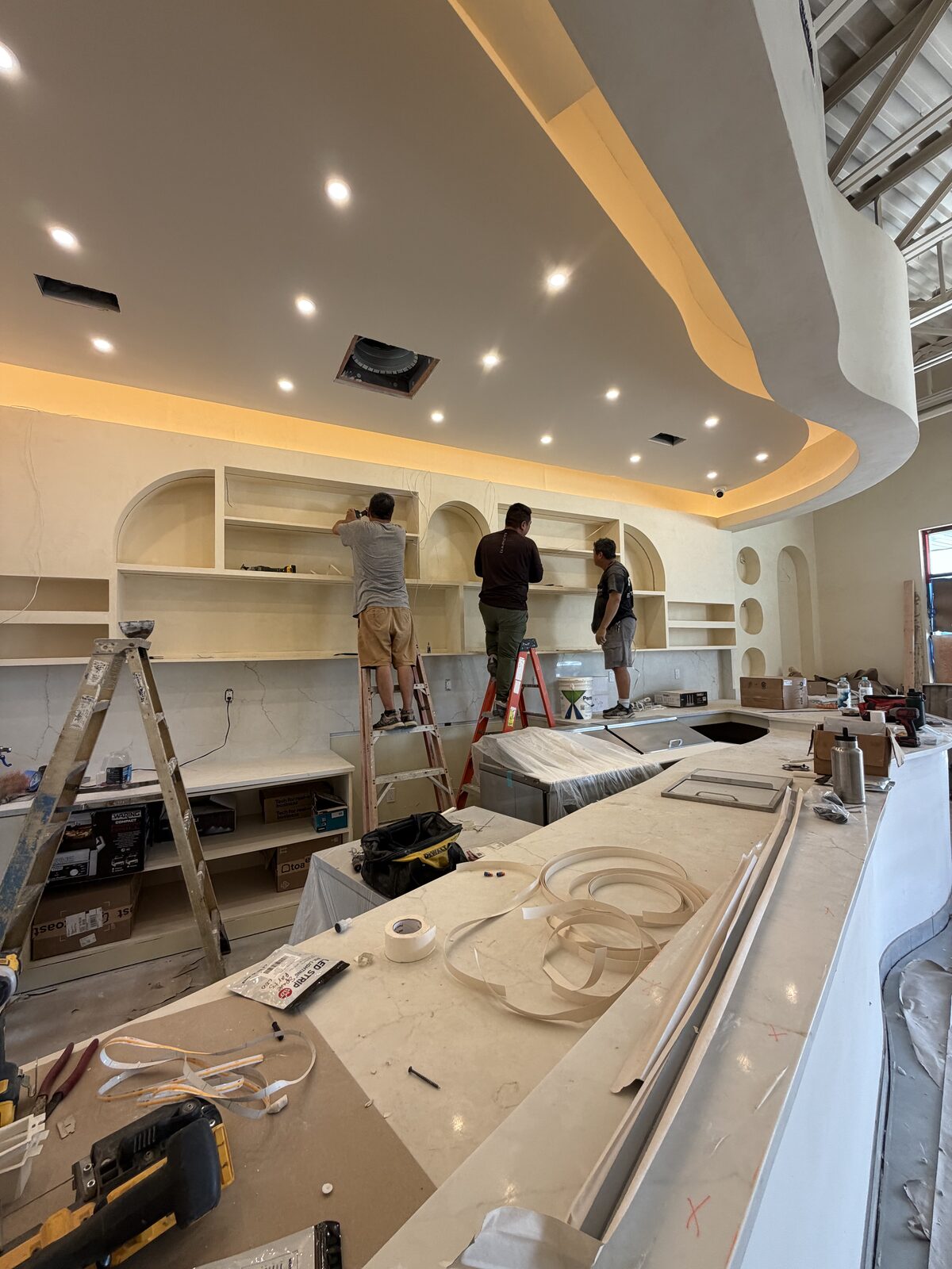 Arched back-bar shelving and marble counter installation in progress