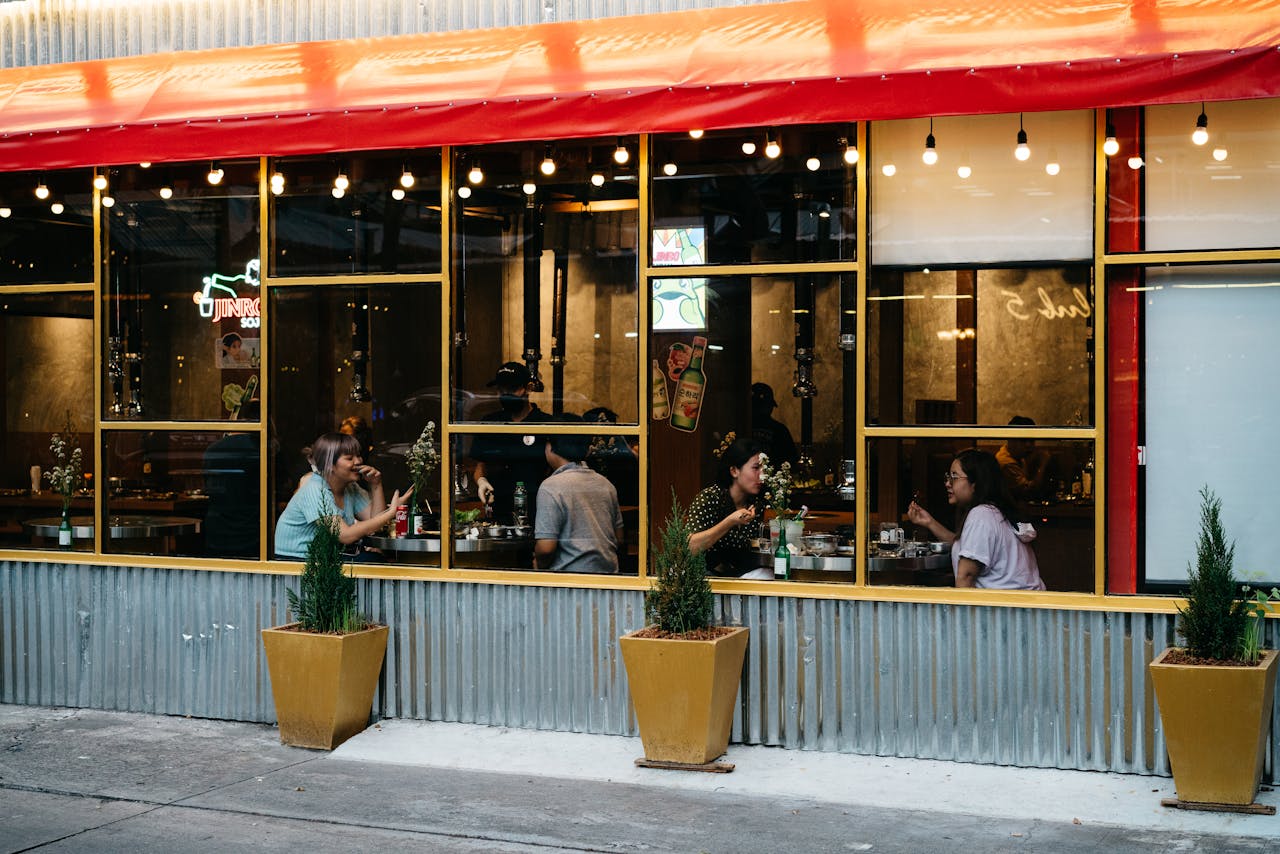 home Friends enjoying a meal at an outdoor restaurant with a vibrant red awning.