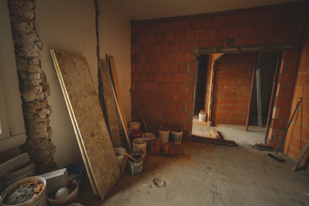 A red brick wall under construction with tools and materials scattered around in a renovation project.