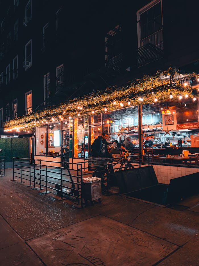 Charming urban restaurant illuminated by warm string lights on a cozy night setting.